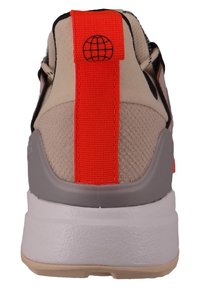 Beige sneaker with a textured fabric upper, gray sole, and bright orange heel tab featuring a globe logo.