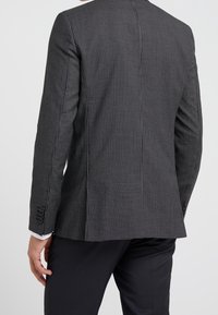 Czarna i biała marynarka w wzory o dopasowanym kroju, teksturowanym materiale i subtelnych cekinowych detalach. Posiada mankiety na jeden guzik i wentylowane plecy.