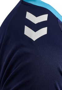 Marinblå sporttröja av texturerat tyg, med ljusblå kant och två stora vita vinkelrader på baksidan.