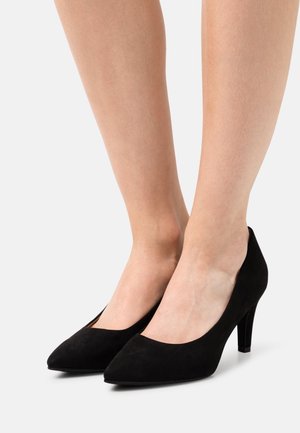 Escarpins noirs en daim à talons hauts avec un bout pointu, présentant une texture lisse et une silhouette élégante, posés sur des talons fins et effilés.