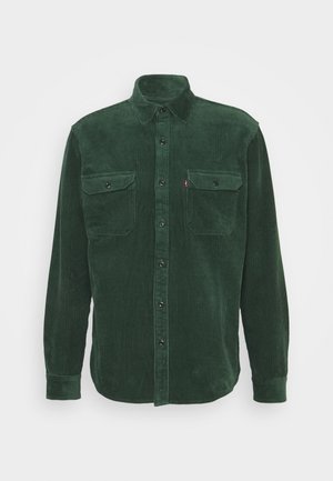 Chemise en velours côtelé vert foncé à manches longues, avec deux poches poitrine à boutons et une fermeture à boutons sur le devant.