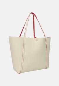 Borsa a spalla color crema con una texture a granuli, accentuata da cuciture rosse e manici. Presenta una cima aperta e un design minimalista.
