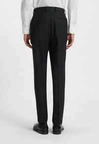 Svarta skräddarsydda byxor med en mjuk textur, figursydd design, bakfickor med knapppardetalj och en lätt veck ner längs benen.