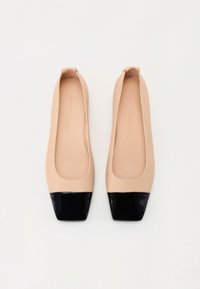 Chaussures plates nude avec un bout carré, présentant un cap en cuir verni noir brillant et un upper en matériau mat lisse.