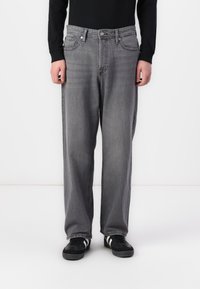 Grey denim jeans with a relaxed fit, featuring a classic five-pocket design, subtle fading, and contrasting stitching. Paired with black sneakers.