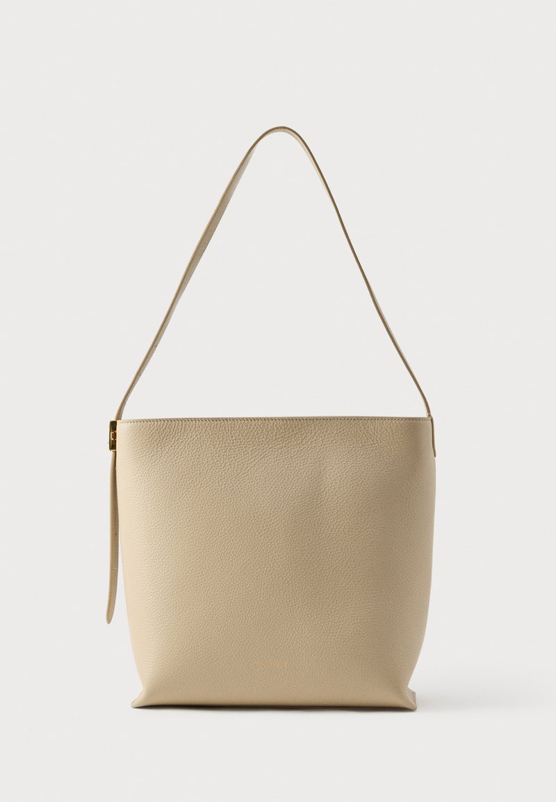 Beige leren schoudertas met een zachte textuur, minimalistisch design, enkele riem en een discrete bovenste ritssluiting.