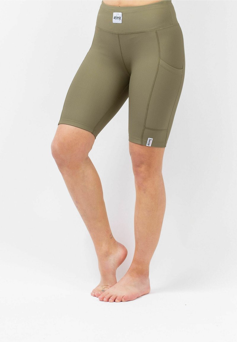 Olijfgroene geribde fietsshorts met een hoge tailleband, voorzien van zijzakken en een klein merkelogo op de zoom. Zachte, rekbare stof.