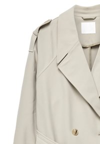 Beige trenchcoat med brede slag, skulderstropper, knaplukning og et stofbælte, der kan ses nær kraveområdet.