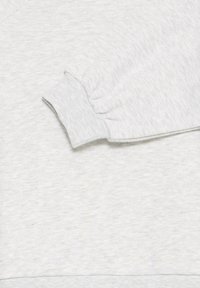 Sudadera gris claro centrada en el detalle de los puños. El material es suave con un acabado texturizado; presenta puños y dobladillo acanalados.
