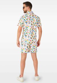 Kurzärmliges weißes Hemd und Shorts-Set mit einem bunten Multi-Muster-Design, das Sterne, Lippen und Regenbogenakzente zeigt. Aus Baumwollmaterial.