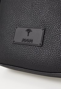 Borsa in pelle nera con texture, caratterizzata da un'emblema rettangolare nero con il marchio "JOOP!" e un'icona di palma.