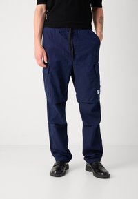 Navy blue cargo pants with a pinstripe pattern, elastic waistband, and drawstring. Features side pockets and a small branded patch.