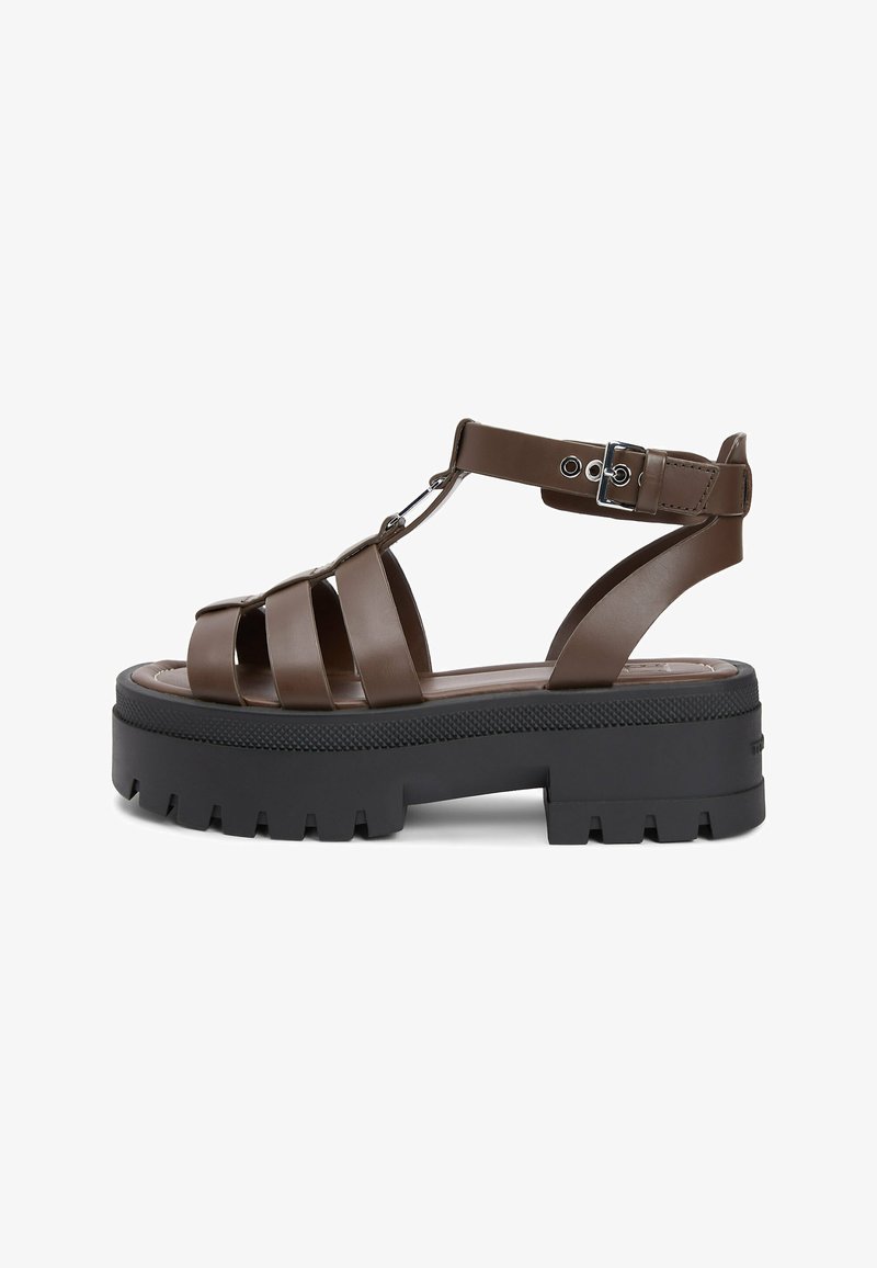 Sandale gladiateur en cuir marron avec semelle épaisse noire à crampons et bride de cheville réglable avec boucle en métal.