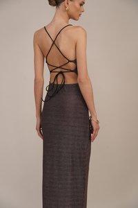 Vedere din spate a unei rochii lungi, mulate, dintr-un material sclipitor închis la culoare. Aceasta prezintă bretele crisscross și un spate deschis cu fundițe.