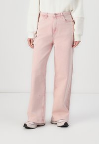 Svetlo roza široke kavbojke z visokim pasom, ki vključujejo sprednje žepe in zapiranje na gumb. Gladek denim material z rahlim zbledelostjo.