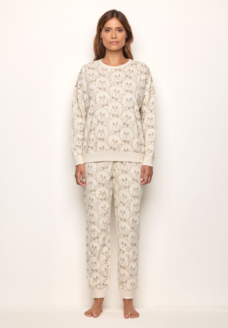 Conjunto de loungewear de color beige claro que incluye un sudadera de cuello redondo y pantalones tipo jogger. Ambas piezas están adornadas con un patrón repetido de caras de oso.