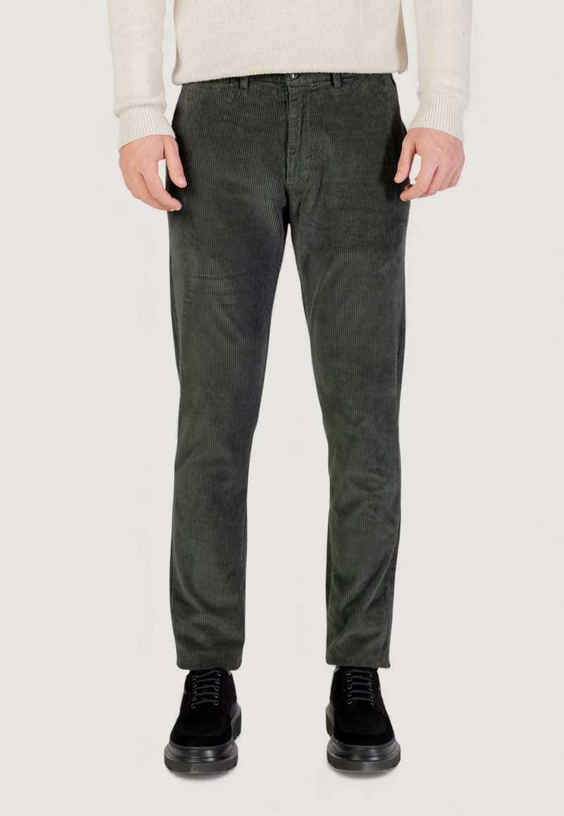 Pantaloni verdi scuro in velluto a coste con design slim fit, caratterizzati da una texture a coste verticali e classica tasca a cinque tasche, abbinati a scarpe nere.