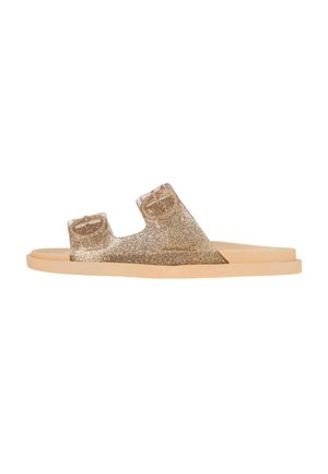 Infradito glitter dorate con due cinture larghe, suola piatta color tan e materiale superiore trasparente che mette in mostra dettagli scintillanti.