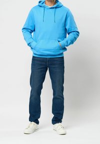 Světlomodrá mikina s kapucí, s kapesní kapsou, nastavitelným šňůrkovým stahováním a malým logem. Nositelná s tmavě modrými džíny a bílými teniskami.