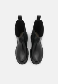 Černé kožené kotníkové boty s hladkým povrchem, elastickými bočními panely a texturovanou gumovou podrážkou. Ucho na zadní straně pro snadné obouvání.