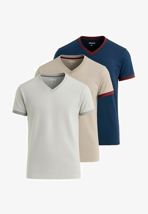 Hvid v-hals t-shirt med korte ærmer, grå kant ved halsudskæringen og ærmerne. Behageligt stof. Modellen bærer grå bukser og accessories.