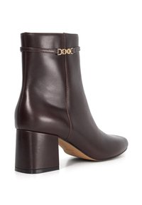 Brown leather ankle boot with a block heel, featuring a gold buckle accent and smooth texture; structured shape with a fitted ankle.