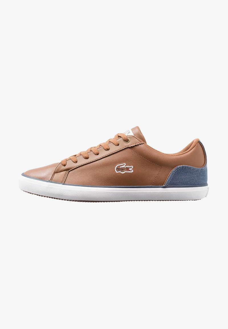 Baskets en cuir marron avec lacets beige, semelle blanche, accent bleu au talon et logo crocodile brodé sur le côté.