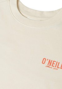 Μπεζ T-shirt με στρογγυλή λαιμόκοψη και πορτοκαλί κείμενο "O'NEILL Since 1959" τυπωμένο στην πάνω αριστερή πλευρά του στήθους.