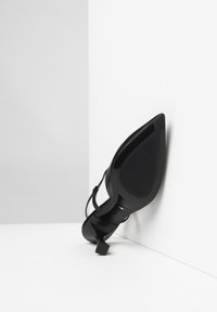 Scarpa nera con tacco alto e punta affusolata, dotata di suola texturizzata e sottile cinturino alla caviglia. Materiale liscio con finitura lucida.