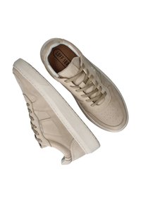 Beige leren sneakers met een gladde textuur, ronde neus, platte veters, geperforeerde details op de neus en een contrasterende witte zool.