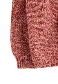 Stykke af tyk, ribbet strikket stof med blandede røde, orange og cremefarvede garner, der danner et tekstureret, varmt mønster.