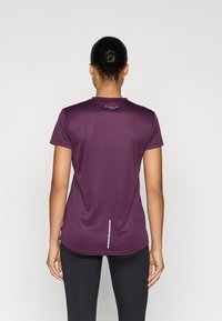 Lühikeste varrukatega lilla sportlik särk, valmistatud kergest kangast, millel on ümar serv ja seljal nähtavust parandav helkurtriip.