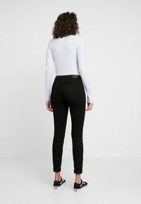 Svarta skinny jeans med en klassisk design med fem fickor, ihopparat med en ljusblå långärmad topp. Mjuk bomullsblandning, ankellång.