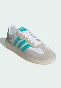 Adidas sneakers featuring a grey suede and white leather upper, turquoise accents, flat white laces, and a translucent rubber sole.