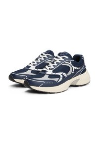 Granatowe siateczkowe sneakersy z srebrnymi akcentami, białymi sznurowadłami i grubą kremową podeszwą. Posiadają perforowany wzór, który zapewnia przewiewność.