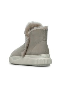 Stivale alla caviglia in suede grigio con un morbido rivestimento peloso, punta arrotondata e suola in gomma bianca testurizzata con scanalature orizzontali.