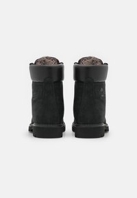 Svarta mocka anklarstövlar med en vadderad krage, texturerad yta och foder av päls. Inbyggd gummisula för grepp och hållbarhet.