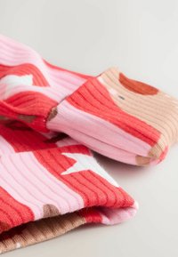 Stickade strumpor i nyanser av röd, rosa och beige; har en ribbad textur med mönster av djuransikten och geometriska former.