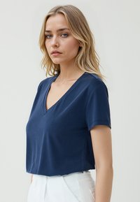 Granatowa koszulka V-neck z krótkim rękawem, wykonana z miękkiego materiału, z luźnym krojem i minimalnymi detalami w szwach.