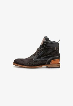 Zwarte kalfsharen enkellaarsjes met bruine leren accenten, ronde neus, vetersluiting en zichtbare profielzool. Beschikt over twee knopen op de enkel.