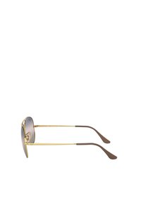 Occhiali da sole in metallo dorato con terminali in gomma marrone, forma aviatore, lenti grigie sfumate e dettagli minimi sulla montatura.