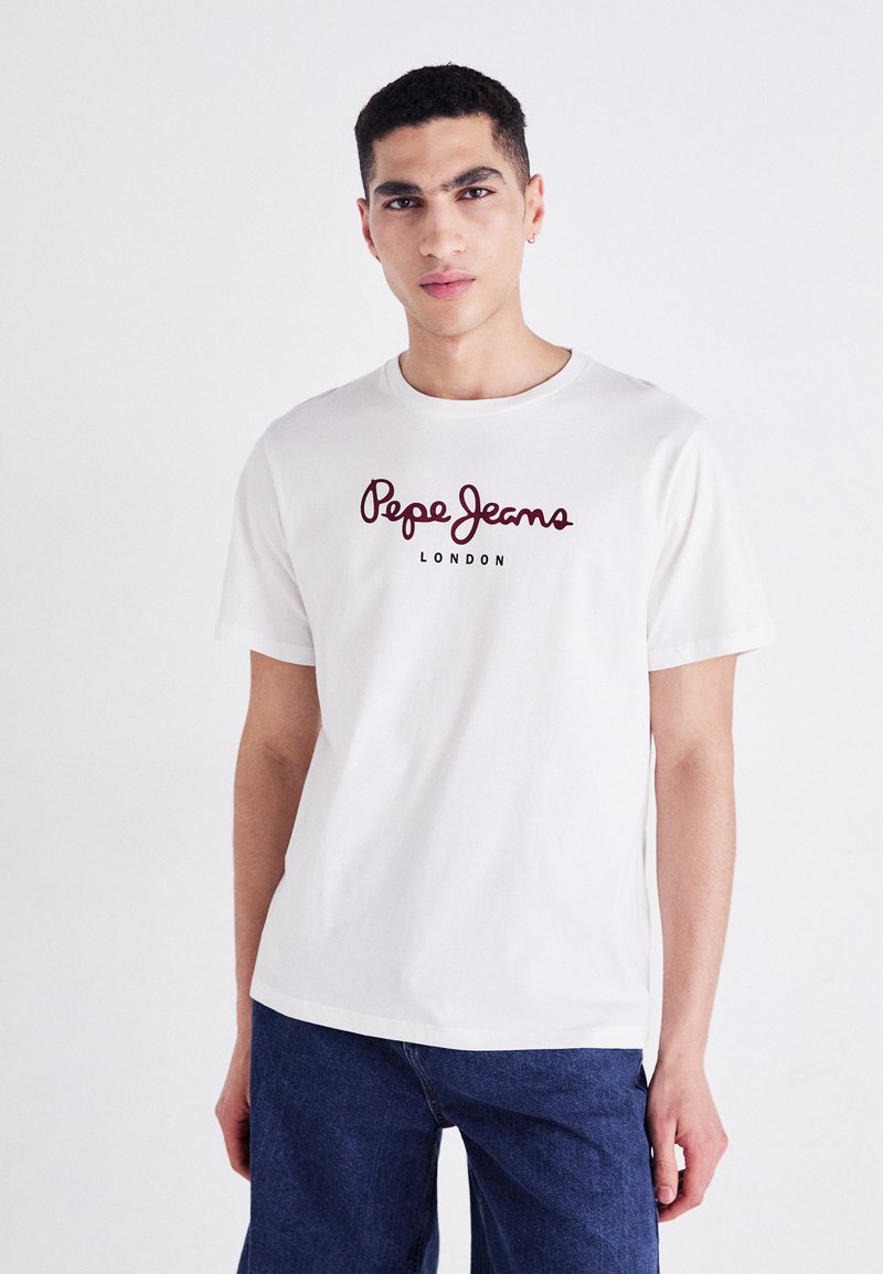 Hvit bomulls t-skjorte med rød kursiv "Pepe Jeans" logo og "LONDON" i mindre tekst under. Korte ermer og rund hals, ledig passform.
