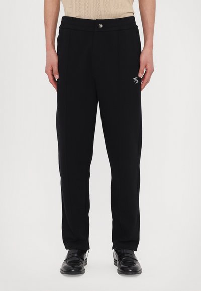 Black trousers made from a soft fabric, featuring a straight leg design, front pleats, and a small embroidered logo on the left thigh.