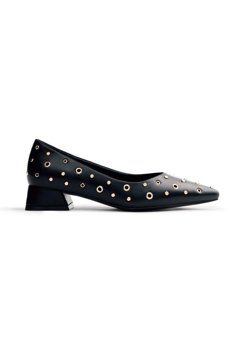 Zapato de charol negro con punta afilada y tacón bajo en bloque. Acentuado con ojales de metal en tono dorado en diferentes tamaños a lo largo de la parte superior.