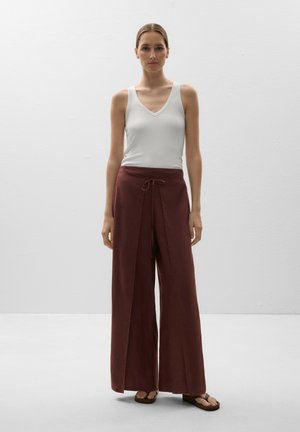 Top alb fără mâneci, cu decolteu adânc în V, asortat cu pantaloni burgundy confortabili, cu croială largă, având talie cu șnur. Design minimalist, completat cu sandale plate.