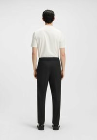 White short-sleeve shirt paired with black, tailored trousers featuring an elastic waistband, smooth texture, and two back pockets.