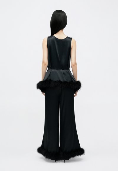 Salopetă din satin negru cu talie peplum, având margini din blană artificială neagră la tivul pantalonilor. Textură netedă cu un design structurat.