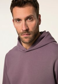 Felpa con cappuccio di colore lavanda tenue, con una texture morbida e cappuccio regolabile con cordino. Il design presenta una vestibilità comoda e cuciture dettagliate.
