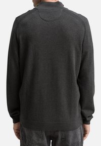 Pull en maille gris foncé avec un col montant, des poignets et un ourlet côtelés ; le tissu présente une texture lisse avec des détails de couture subtils.