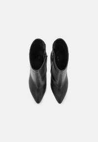 Czarne botki za kostkę z fakturowaną skórzaną wykończeniem w wzór skórki gada. Posiadają spiczasty czubek oraz boki zapinane na zamek. Wnętrze wyłożone czarną tkaniną.